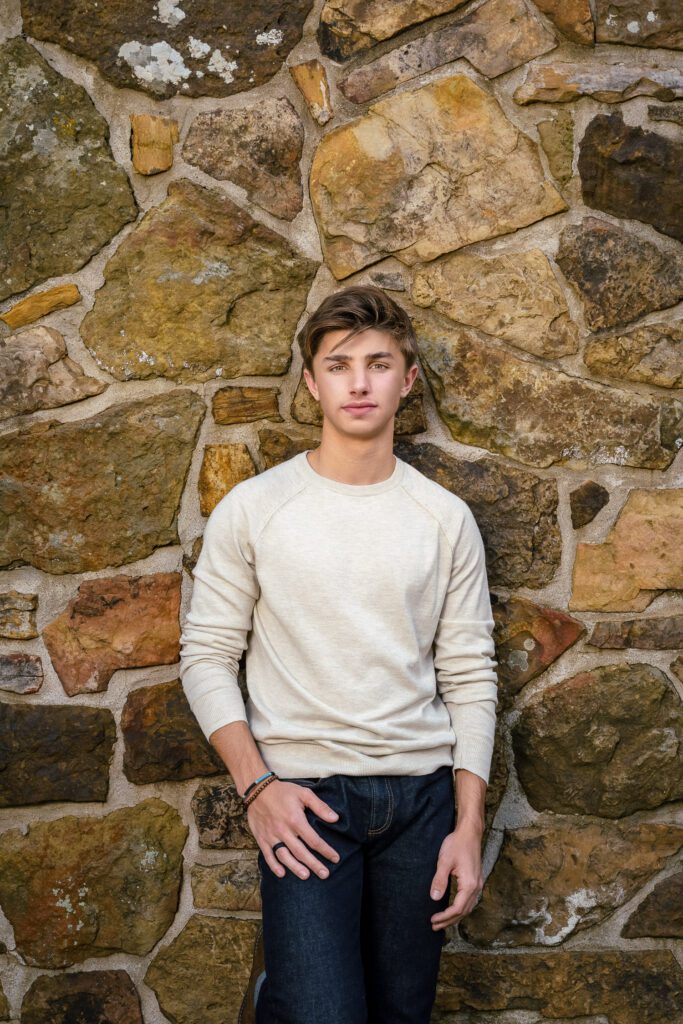 Senior guy standing in front of brown walk wall with sleeves rolled up
