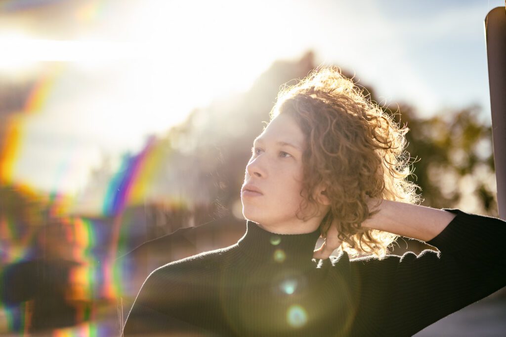 senior guy with long hair has hand in hair with sun spots