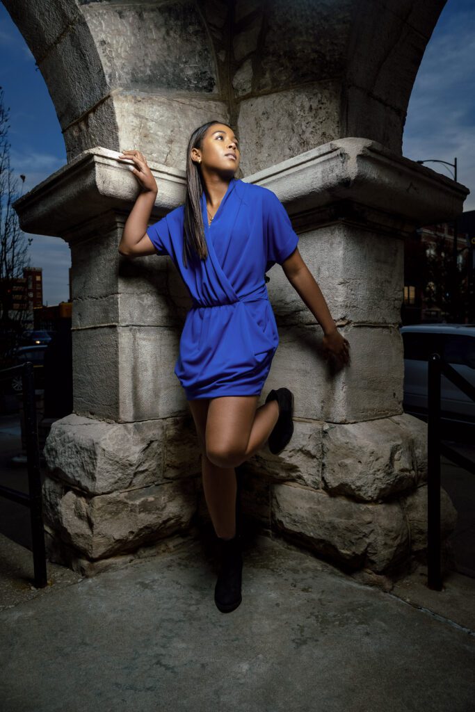 senior girl poses on concrete column wearing blue dress in Columbia, Missouri.