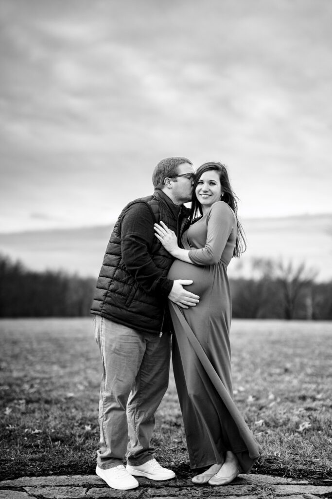 winter maternity session in columbia missouri stephens lake park with purple maternity dress. husband and wife kissing