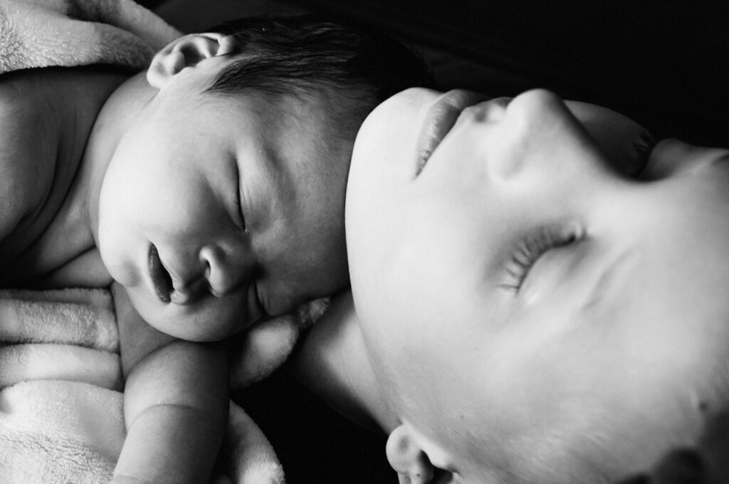 newborn baby laying on big brother's chest asleep