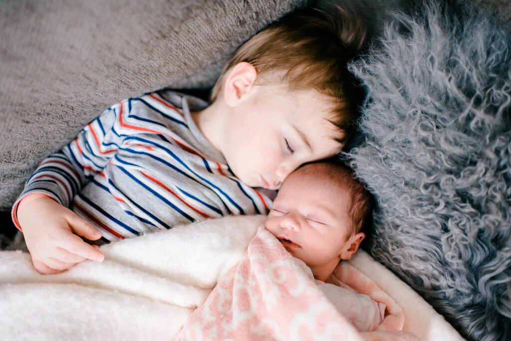 big brother asleep next to newborn sister at home in Columbia, MO