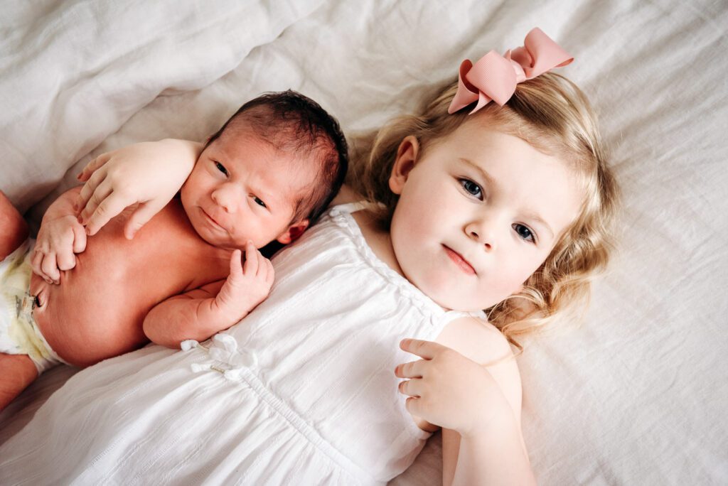 big sister laying next to newborn on bed in Columbia, MO