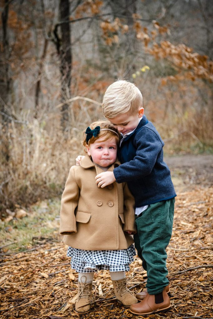 brother consoling little sister in fall leaves Columbia, MO