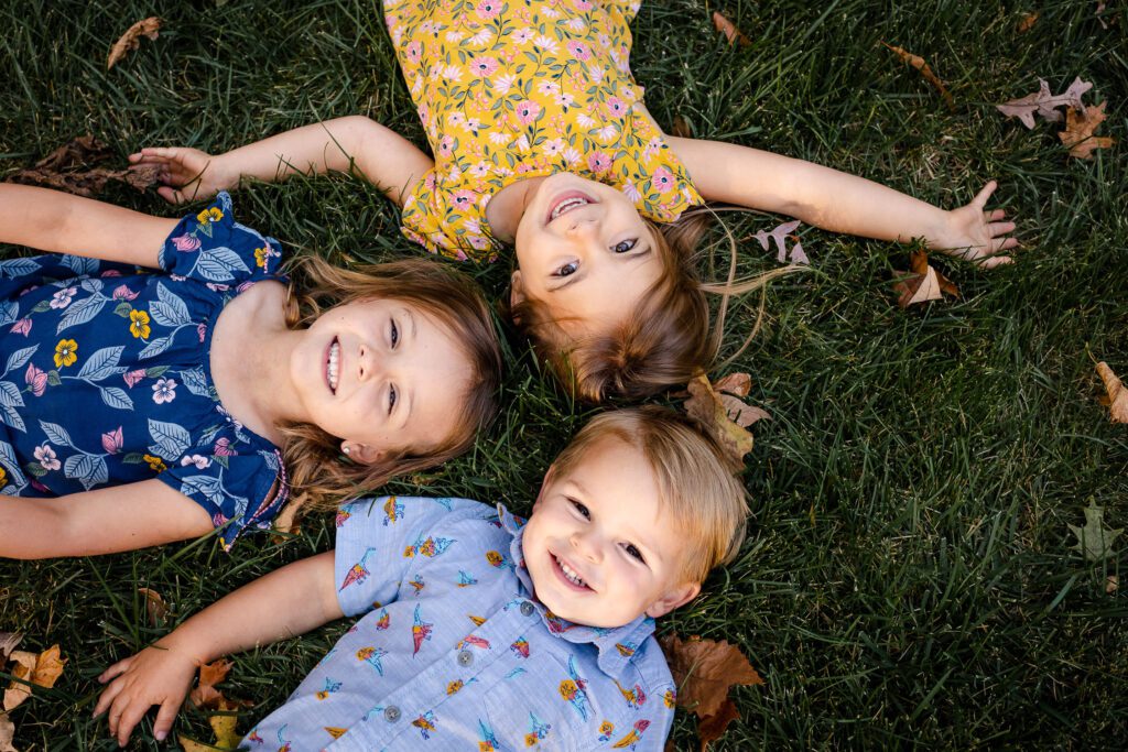 brother and sisters laying in grass smiling