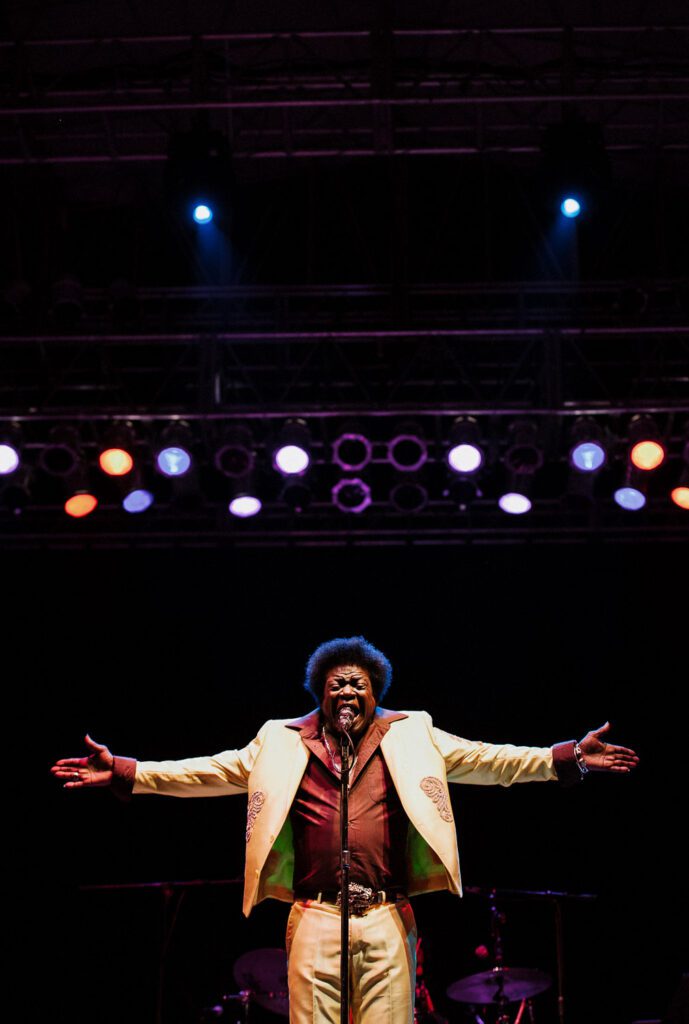 Charles Bradley holds arms out while singing