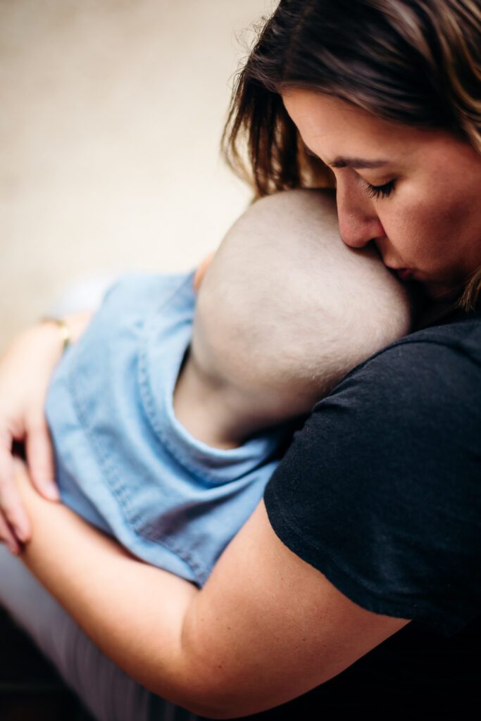 childhood cancer mother kissing son on shaved head