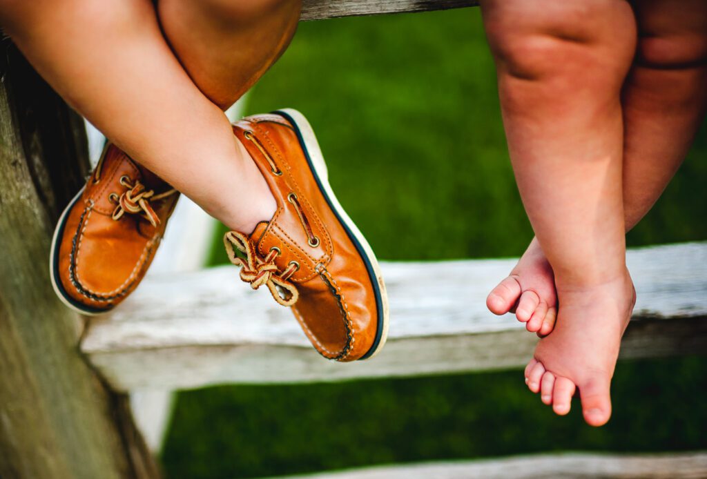 Children sitting on fence with their ankles crossed