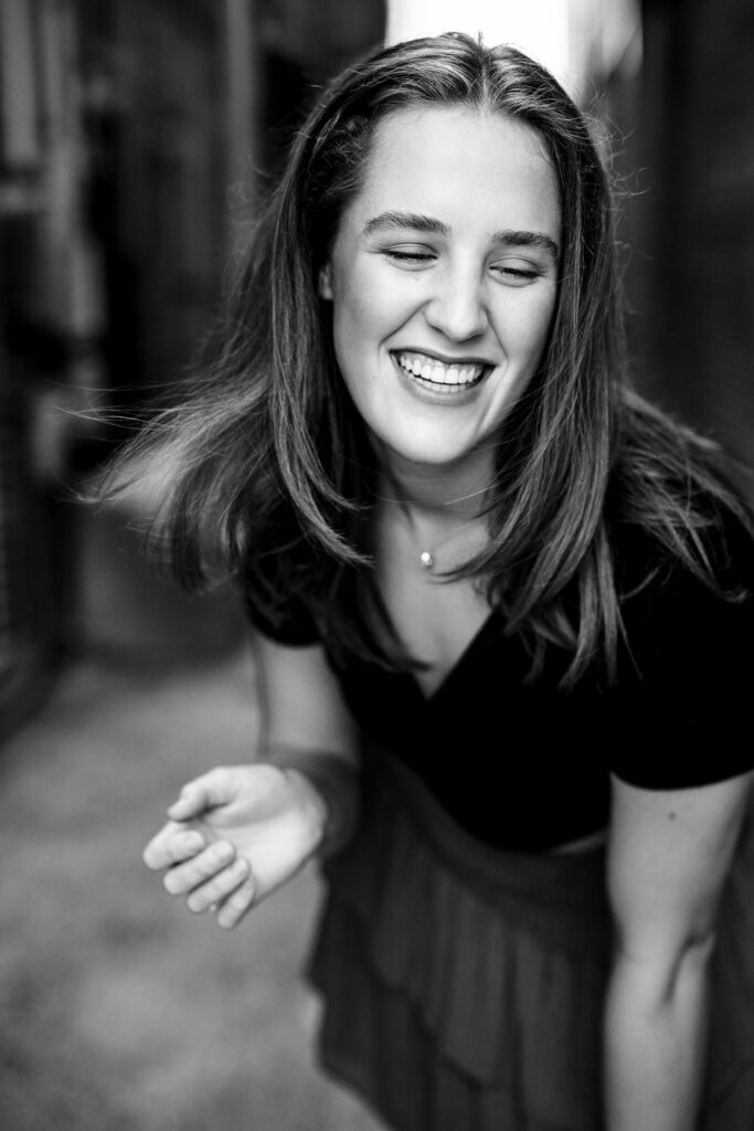 High school senior girl laughs as she leans forward looking over her shoulder