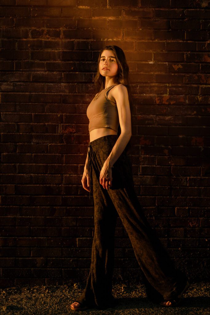 senior girl leans on brick wall with sunshine