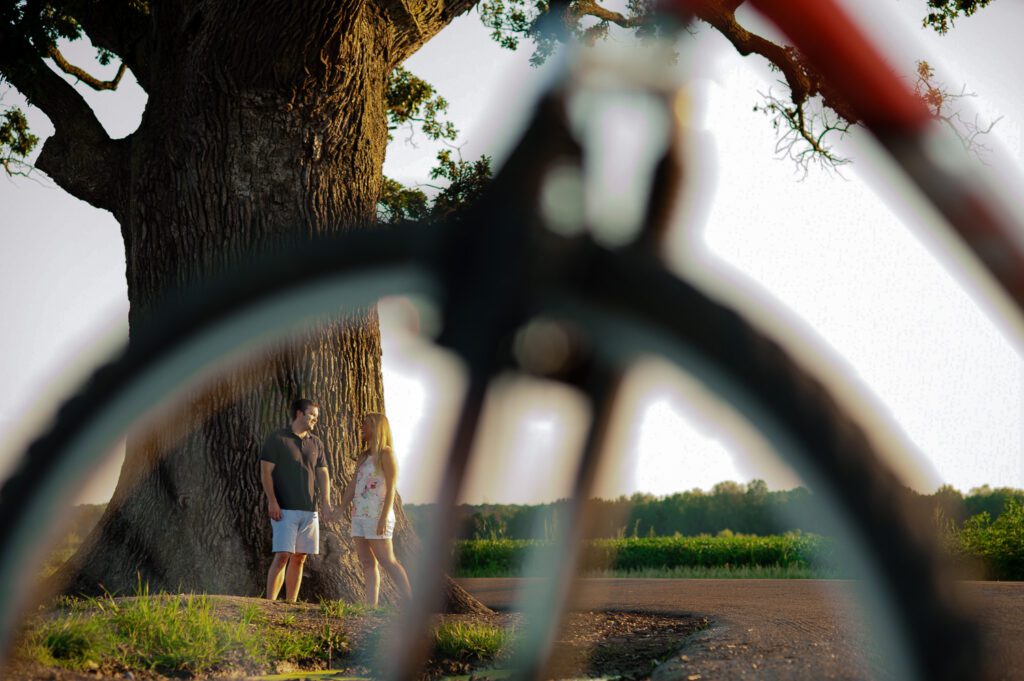 couple standing by big tree with bicycle tire