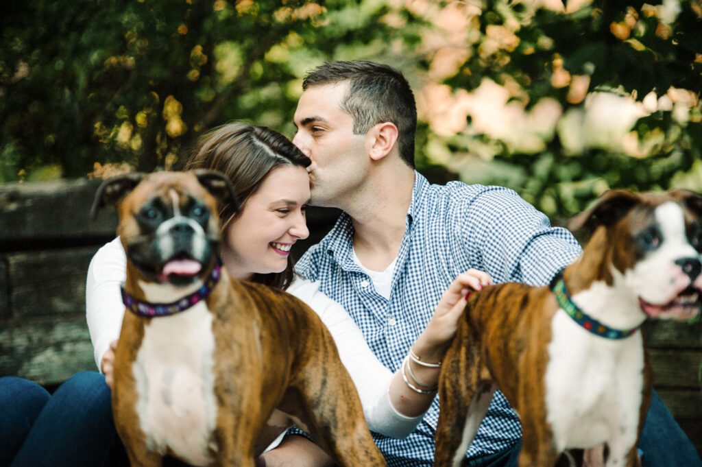 couple kissing with two dogs