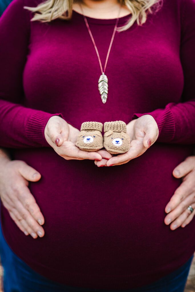 pregnant couple holding baby shoes
