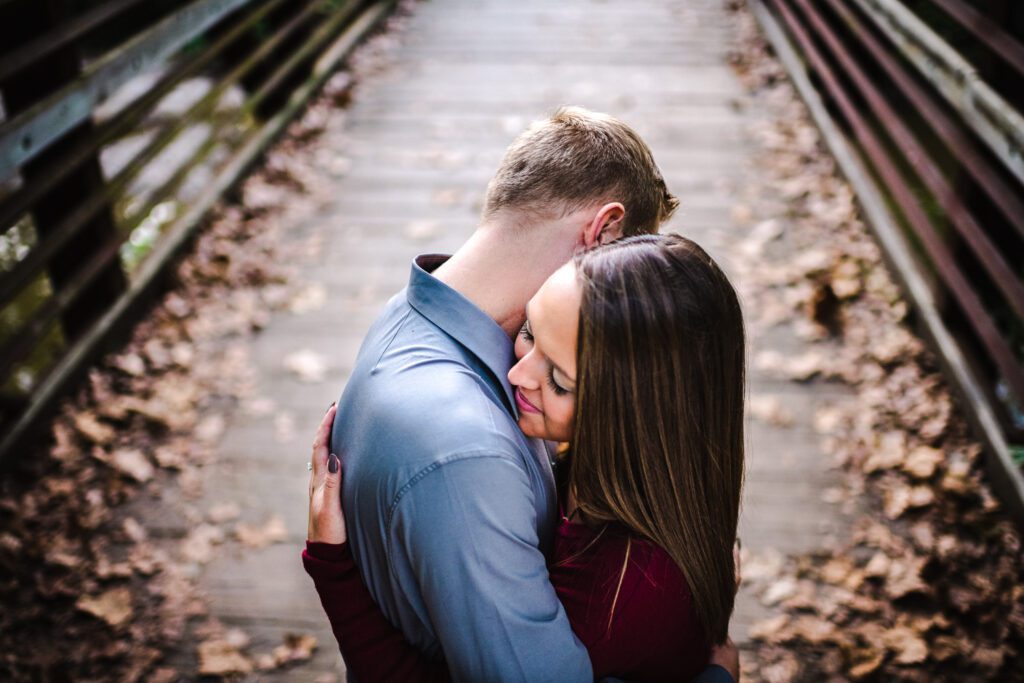 couple hugging on fall leave bridge Katy Trail