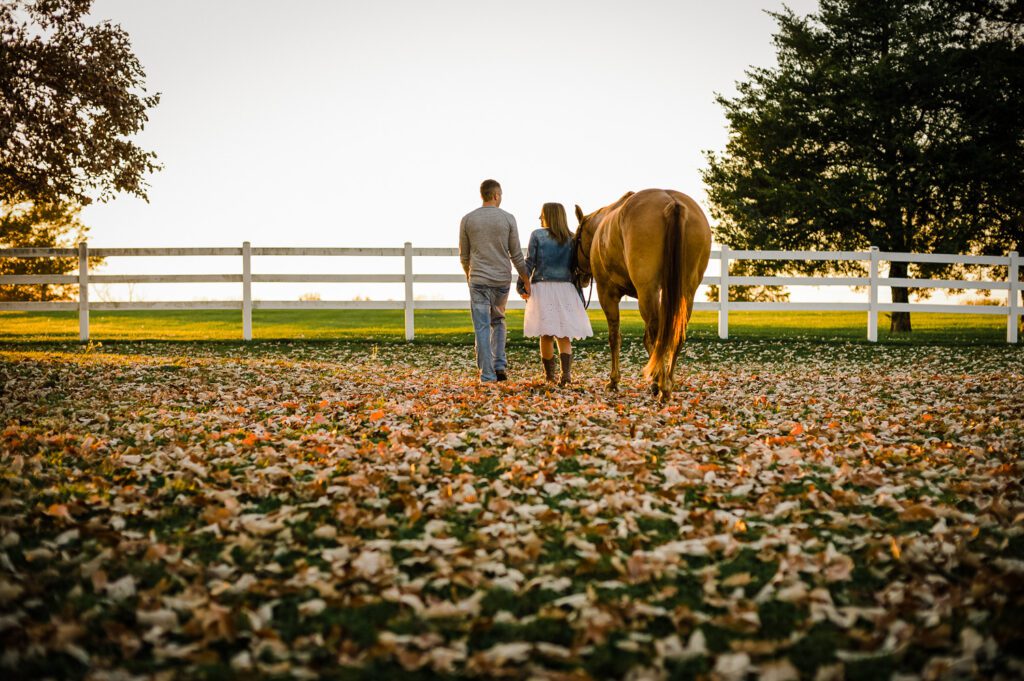 couple holding hands while walking horse