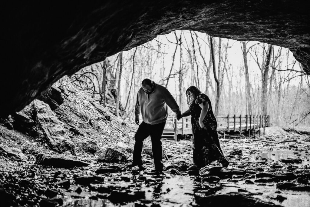 couple walking under rock bridge cave