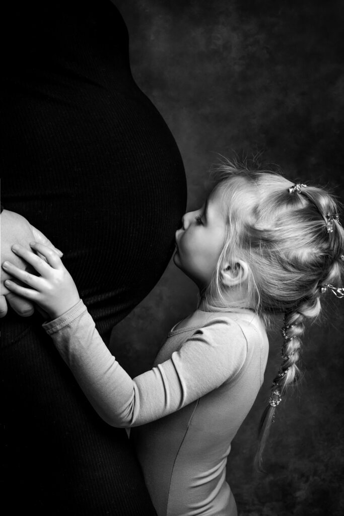 daughter kissing mother's pregnant belly