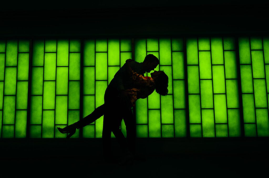 boy dipping girl in front of green lighted background