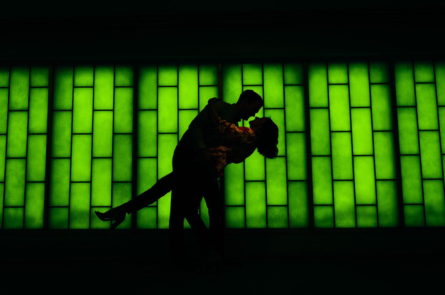 boy dipping girl in front of green lighted background