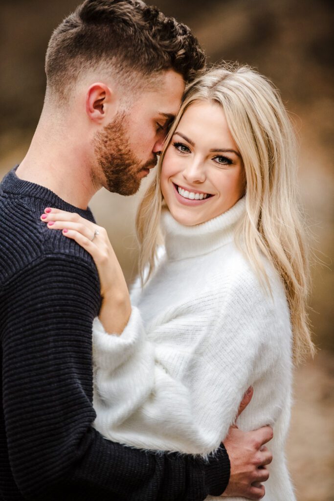 engaged man holding fiance while she smiles