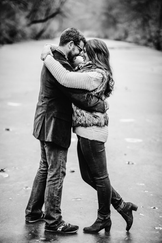 Smiling couple holding each other on frozen creek