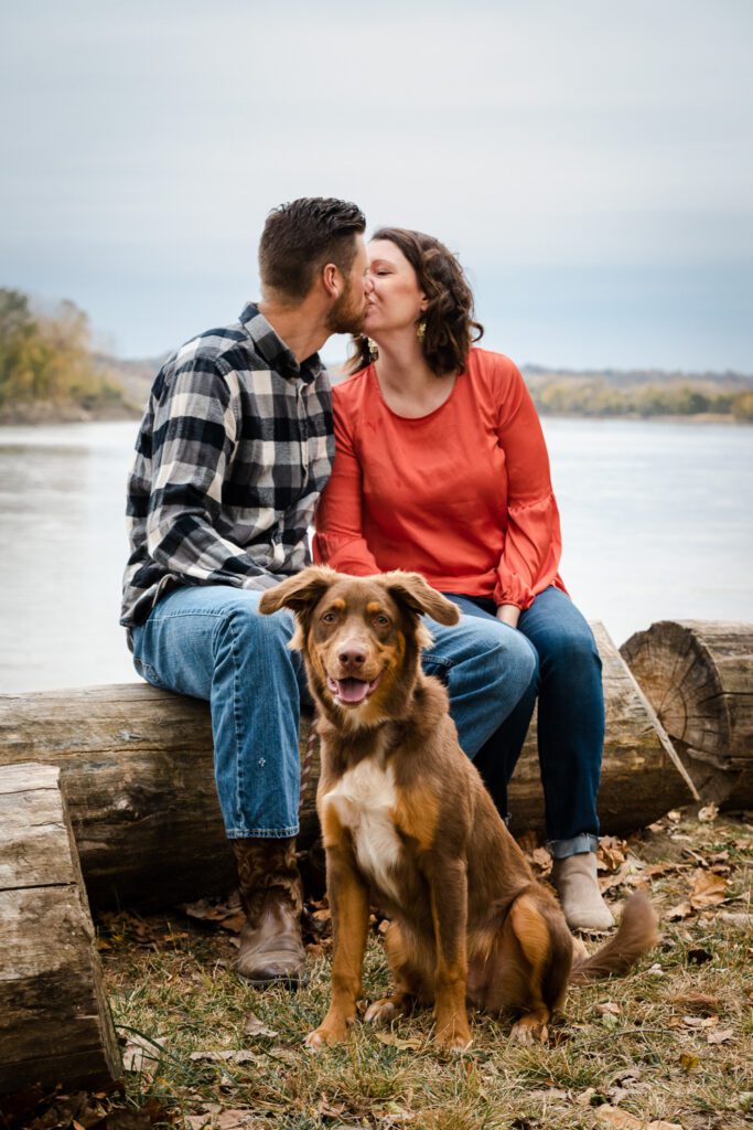 couple kissing in front of Missouri River with dog
