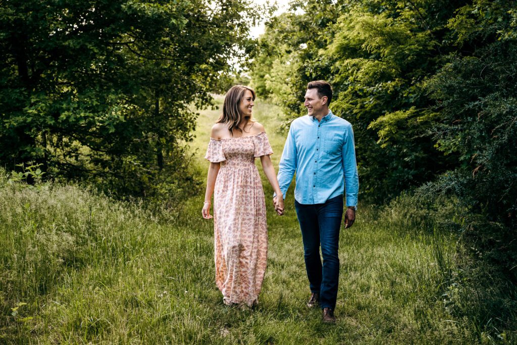 couple walking through greenery woods holding hands