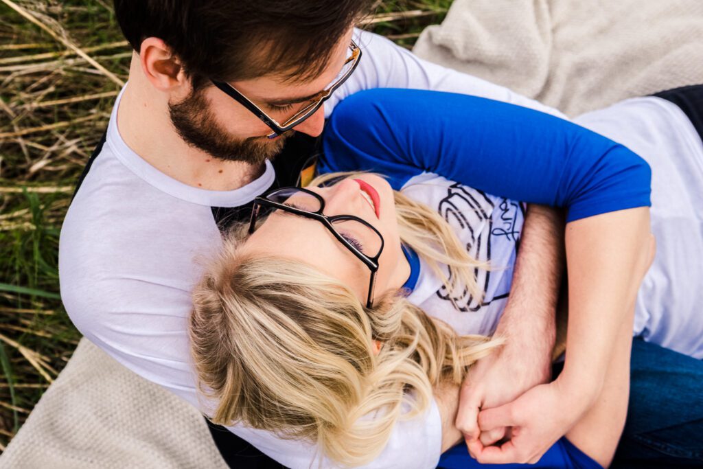 couple wearing glasses holding each other in field