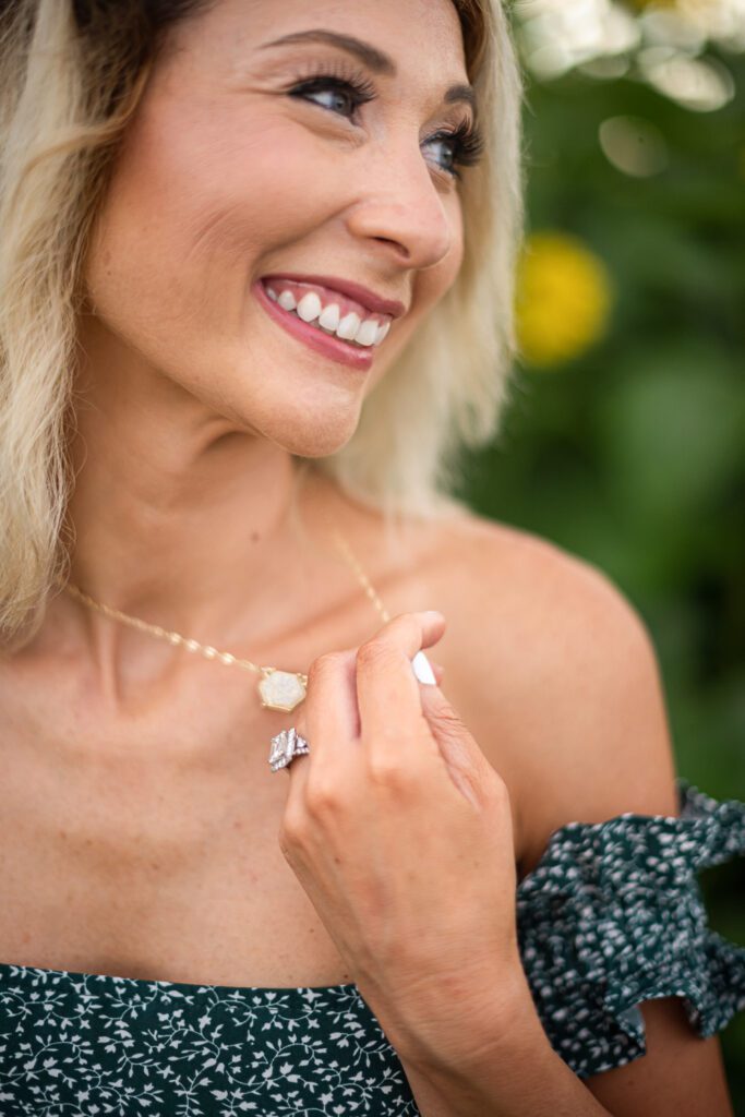 girl smiling playing with necklace showing engagement ring