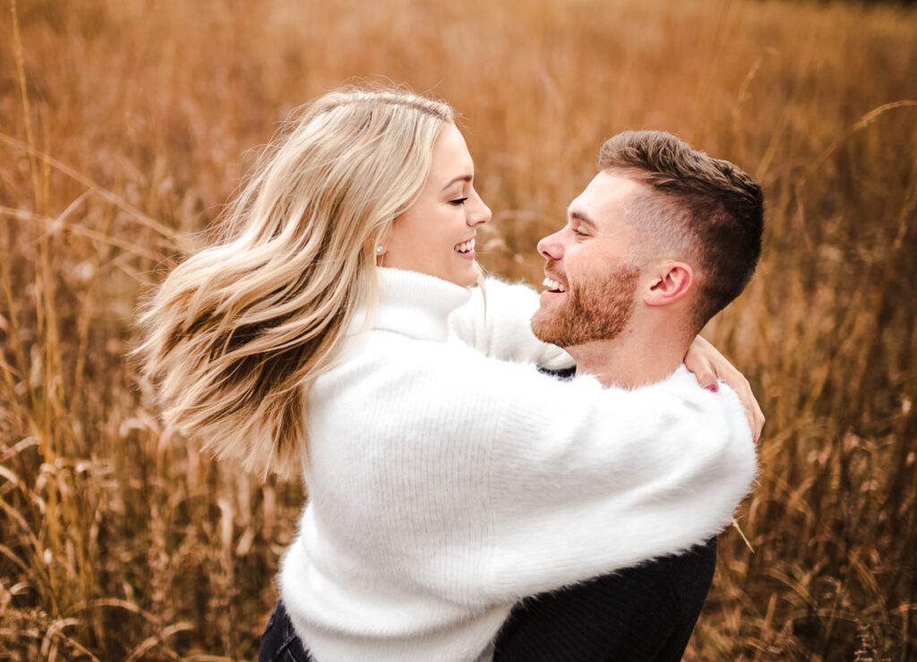engaged man swinging fiance around in field
