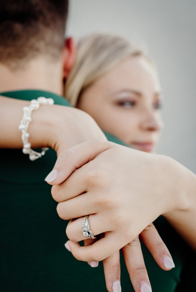 girl holding fiance's neck with engagement ring