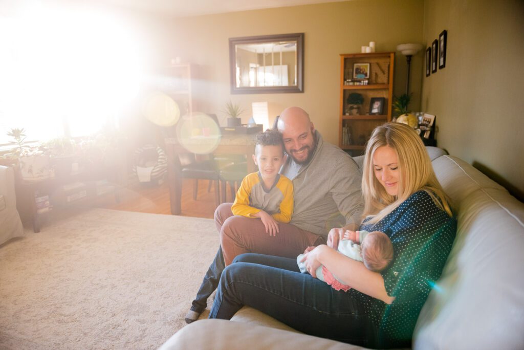 family looks at newborn in a sun drenched room at home in Columbia, MO