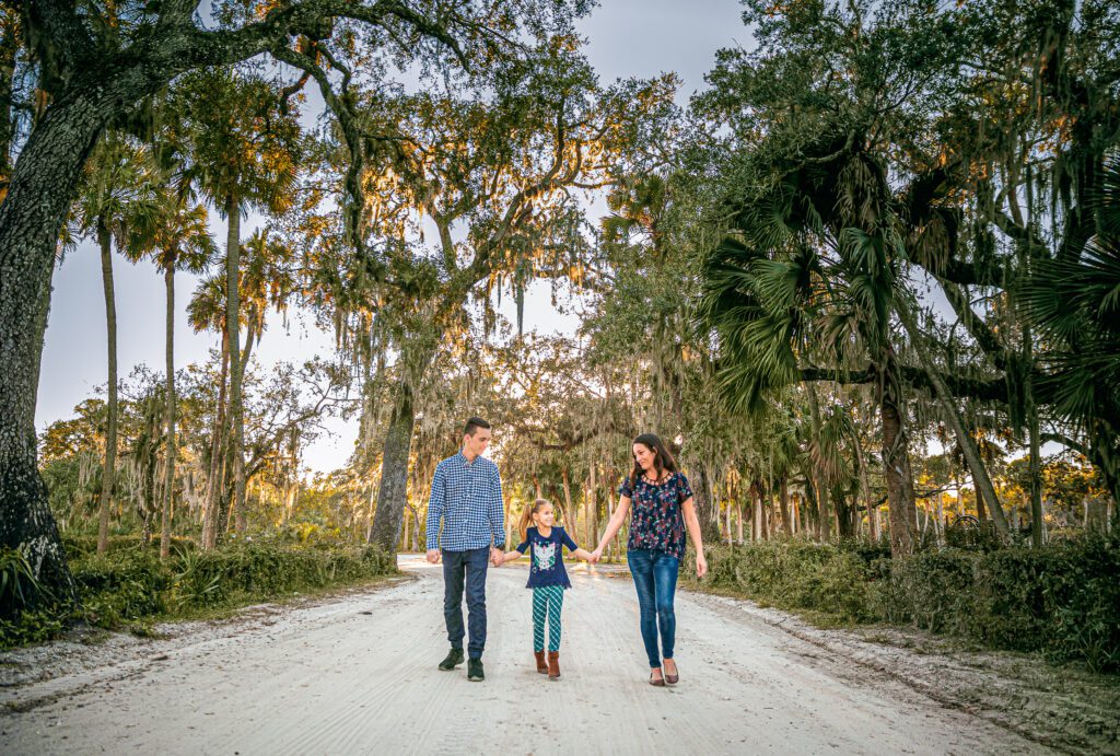 Family walking on the road with palm trees and spanish moss