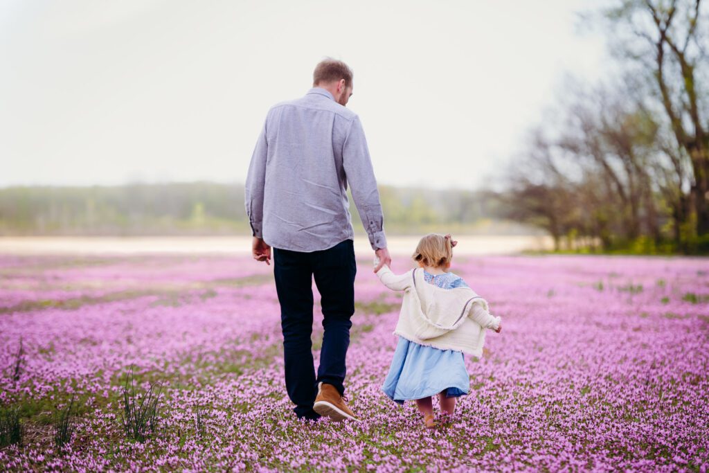 father and daughter walking in a purple field