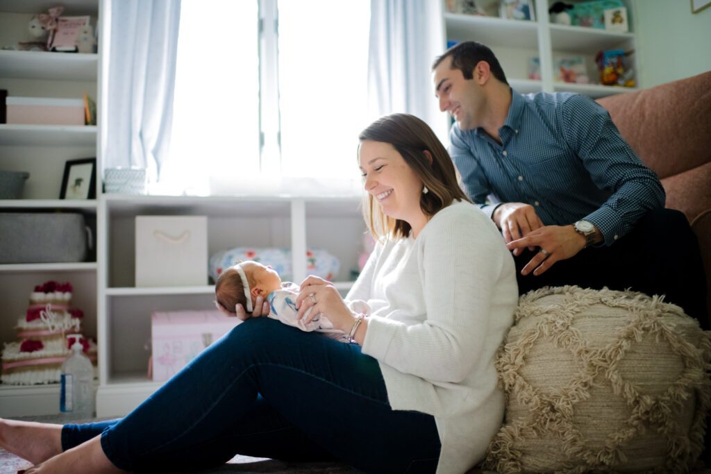 dad looking over mom shoulder at newborn baby at home in Columbia, MO