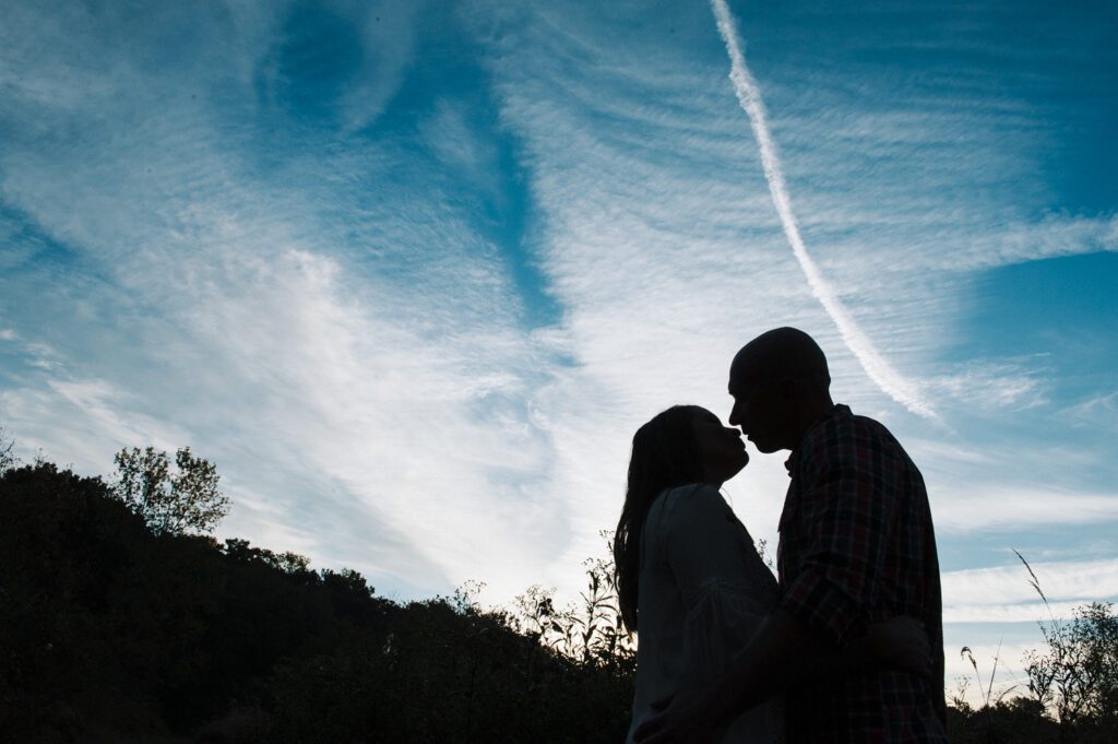 girl kissing boy against blue sky line