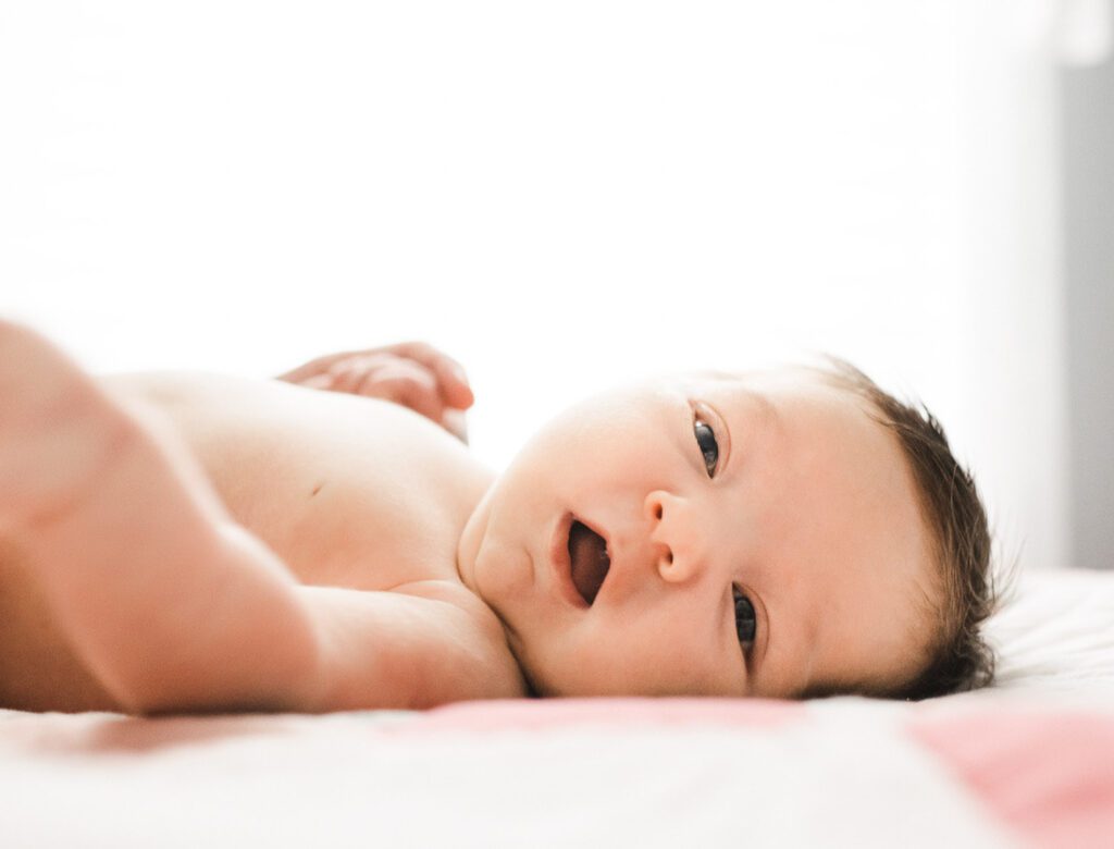 happy newborn baby laying on blanket