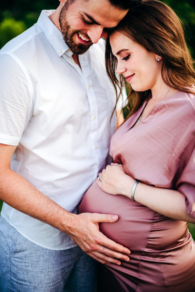 pregnant couple holding belly smiling