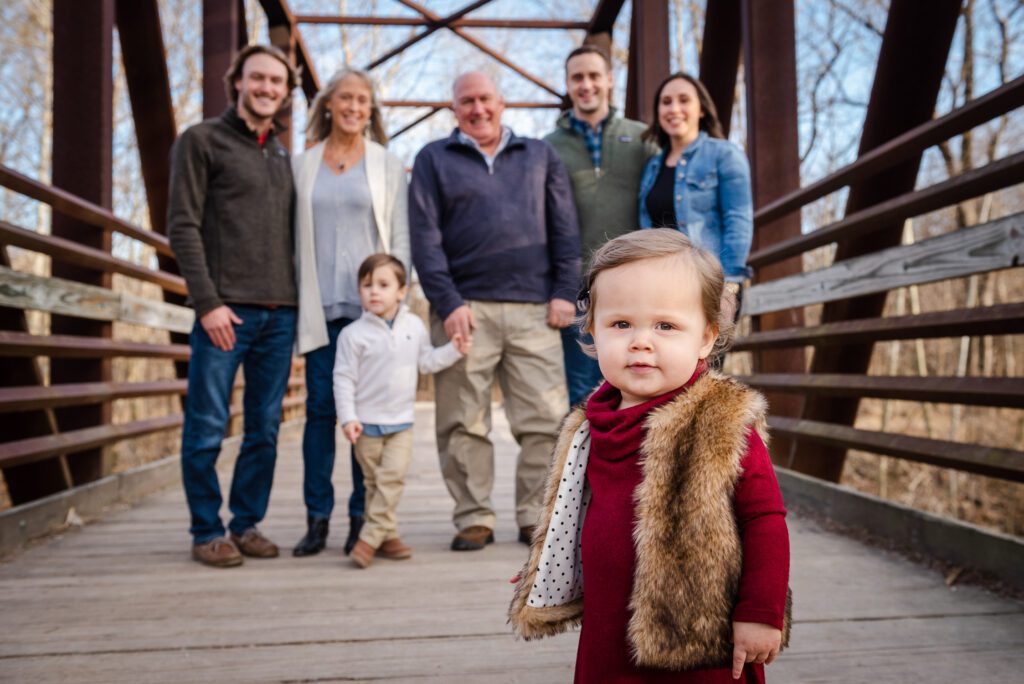 little girl in front of posed family picture on bridge at Katy Trail, MO