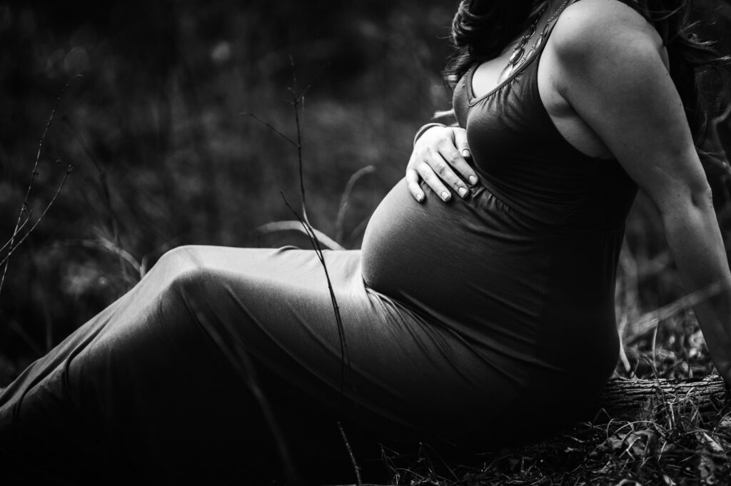 pregnant girl holding belly in field