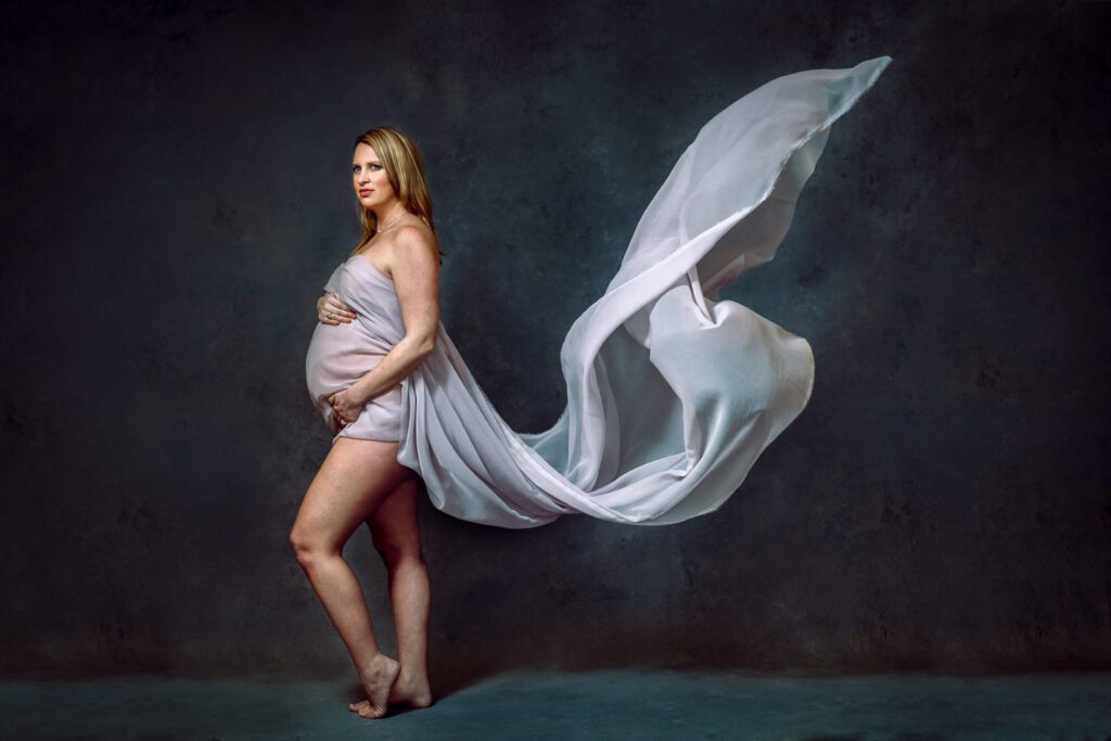 pregnant woman touching stomach with flying fabric