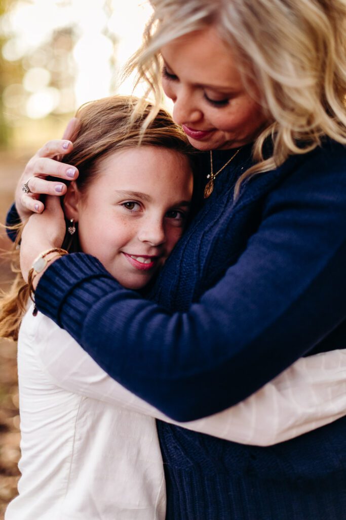 mom in blue sweater hugging daughter