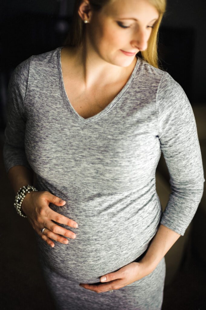 mother holding pregnant belly in dark room