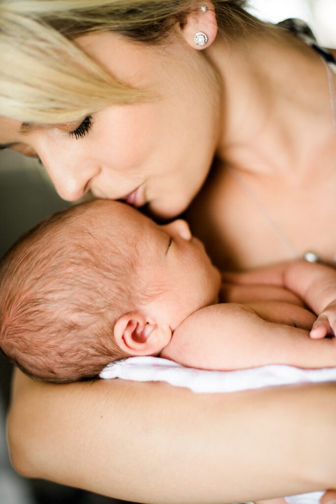 blonde mother kissing newborn's forehead in Columbia, MO