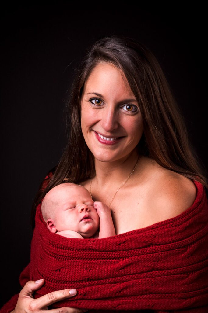 mother wearing red sweater with newborn wrapped inside Columbia, Missouri