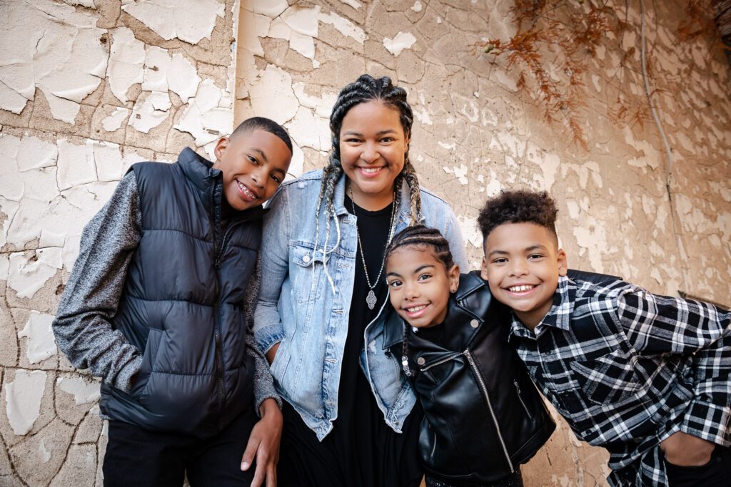 siblings with mother posing in industrial alley