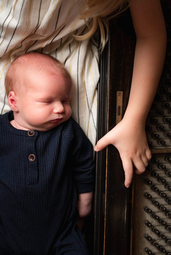newborn laying on piano with sister