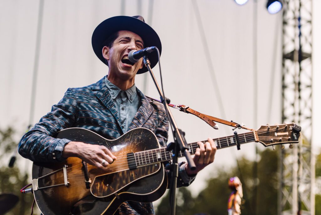 Pokey Lafarge wearing hat and playing guitar