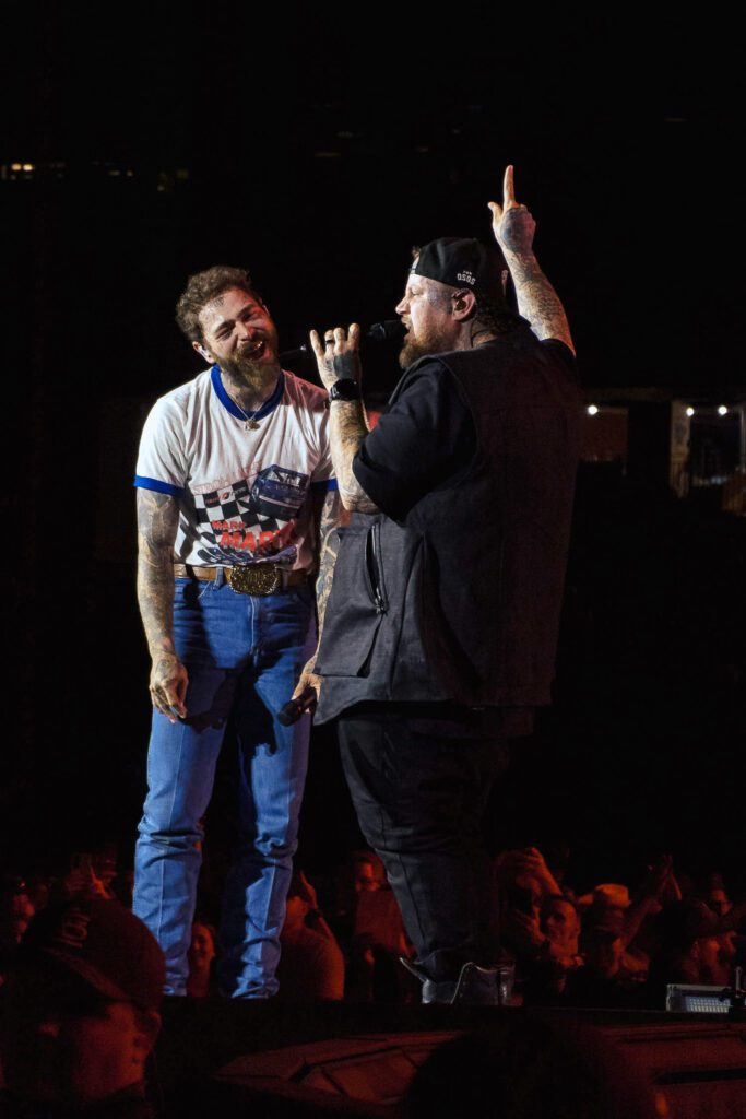 Post Malone laughs as Jelly Roll talks about him in Busch Stadium St Louis Missouri