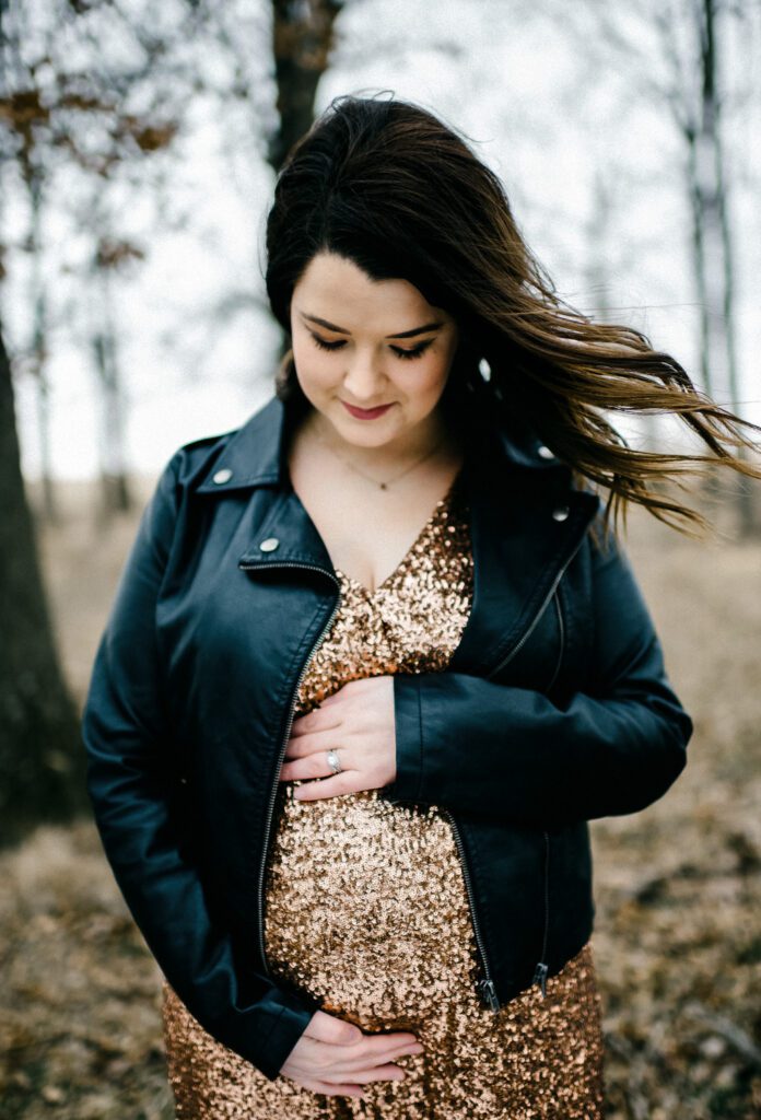 pregnant woman in black leather jacket holding belly